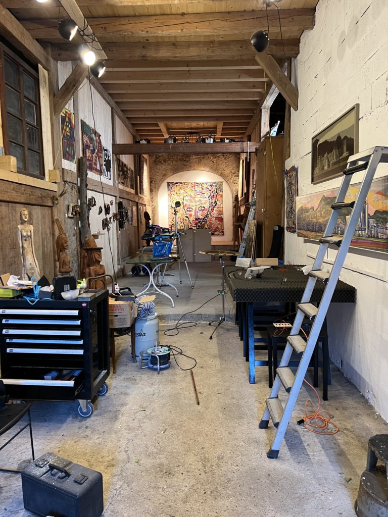 La Grange en cours de montage de l'exposition Hors-Champs : sculptures en bois et toiles colorées aux murs, avec une échelle, une caisse à outils et des câbles au premier plan.